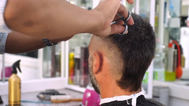 Barber cutting client hair with scissors and comb
