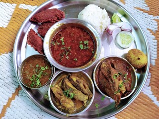A vibrant Indian Fish Thali: a delicious platter featuring various fish preparations, curry, rice, bhakri/roti, and salad, served on a traditional steel plate, highlighting Maharashtrian cuisine.