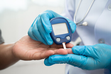 Doctor check diabetes from finger blood sugar level with digital glucose monitor measure and test stripe. © manassanant
