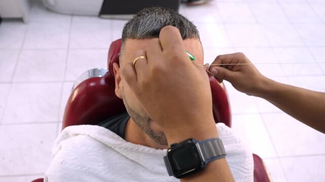 Barber threading client eyebrows with Arabic technique
