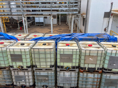 Stacked Intermediate Bulk Containers holding liquid in an industrial environment setting with metal