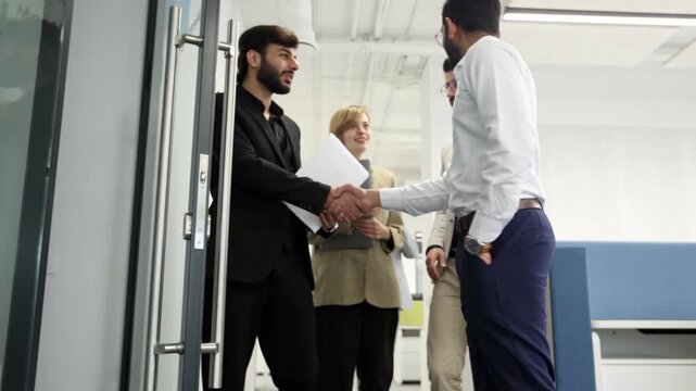 Three men and a woman are walking down a hallway in a business setting