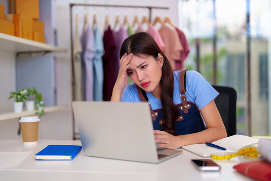 Asian adult woman online clothing business owner managing orders home office desk facing entrepreneurship stress digital marketing challenges retail sales