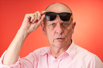 Closeup portrait of a elderly man in studio wearing sunglasses