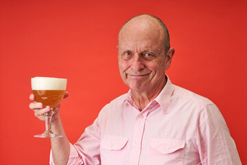 Closeup portrait of a elderly man in studio drinking a trappist beer