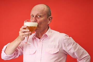 Closeup portrait of a elderly man in studio drinking a trappist beer