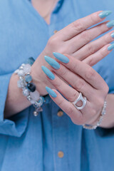 Woman's beautiful hand with long nails and light baby blue manicure	