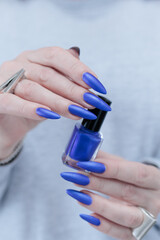 Woman's beautiful hand with long nails and bright blue manicure 