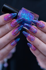 Female hand with long nails and blue and purple thermo french nail polish