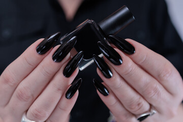 Female hands with long nails and black nail polish