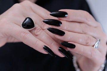 Female hands with long nails and black nail polish