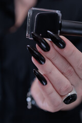 Female hands with long nails and black nail polish