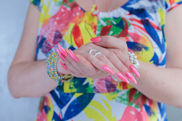 beautiful female hands with long nails and bright neon pink red nail polish