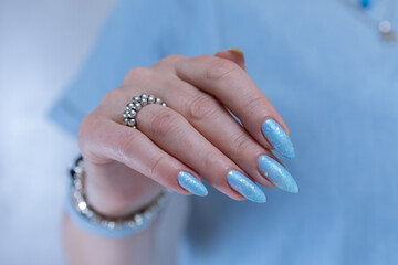Woman's beautiful hand with long nails and light baby blue manicure