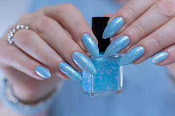 Woman's beautiful hand with long nails and light baby blue manicure	
