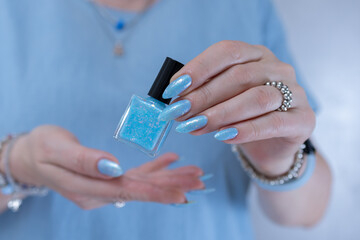 Obraz premium Woman's beautiful hand with long nails and light baby blue manicure