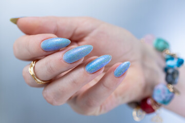 Woman's beautiful hand with long nails and light baby blue manicure	