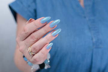 Woman's beautiful hand with long nails and light baby blue manicure	
