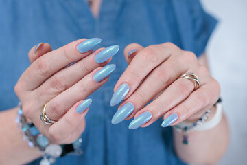 Woman's beautiful hand with long nails and light baby blue manicure	