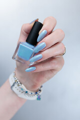Fototapeta premium Woman's beautiful hand with long nails and light baby blue manicure 