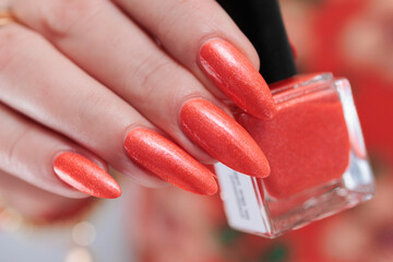 Woman hand with long nails and light orange coral neon manicure