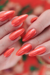 Female hand with long nails and a bright coral orange manicure 
