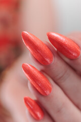 Female hand with long nails and a bright coral orange manicure 
