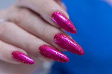 Female hand with long nails and a bottle bright neon pink fuchsia color nail polish