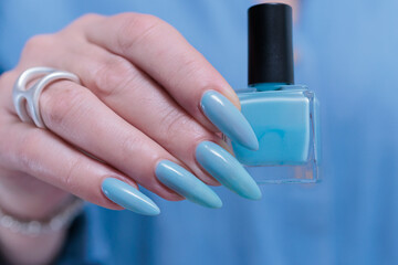 Woman's beautiful hand with long nails and light baby blue manicure	
