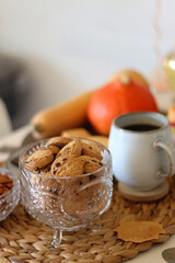 Lit candles, cookies, chocolate, nuts, tea, wine, pumpkins, books, reading glasses and autumn leaves on the table. Autumnal hygge at home. Selective focus.