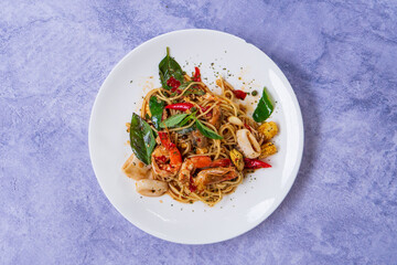Spicy spaghetti with shrimps in tomato sauce close-up on a plate.