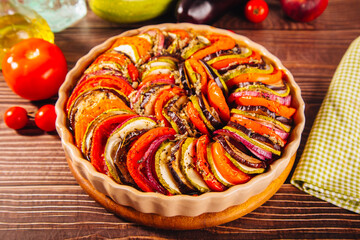 Homemade ratatouille with slices of zucchini, eggplant, tomato, red onion and herbs brushed with olive oil. Vegetarian meal.