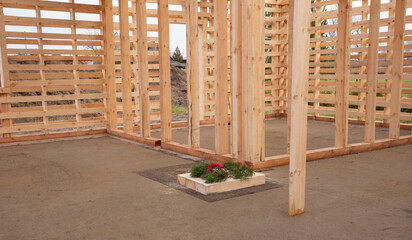Wooden house construction with timber frame and wreath placed in foundation, traditional building ritual symbolizing blessing, eco friendly housing project, sustainable architecture detail