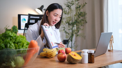 Female nutritionist explaining a health chart in an online consultation with fresh fruits and...