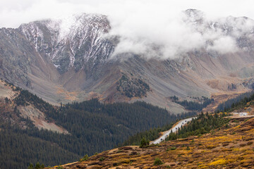 Mist rolls across the forested slopes, softening the sharp lines of the mountains.
