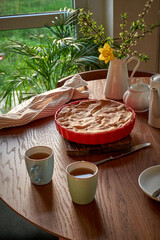 Traditional apple pie on a wooden plate on a light culinary background. Charlotte pie on a platter in closeup. Delicious homemade cakes on the kitchen table