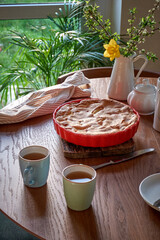 Traditional apple pie on a wooden plate on a light culinary background. Charlotte pie on a platter in closeup. Delicious homemade cakes on the kitchen table