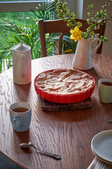 Traditional apple pie on a wooden plate on a light culinary background. Charlotte pie on a platter in closeup. Delicious homemade cakes on the kitchen table