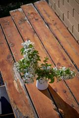 Bouquet of jasmine flowers in a white vase on a wooden table outside