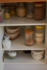 Organizing in kitchen. Pasta and cereals in reusable glass containers in kitchen shelf