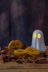 Top view of Halloween cookies with a ghost with glowing eyes, leaves, and nuts, vertically with copy space