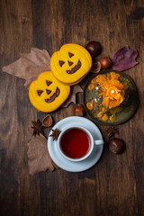 Top view of a cup of tea with Halloween cookies, candles, and nuts, vertically with copy space
