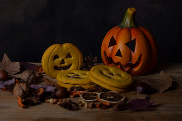 View of a pumpkin with eyes, Halloween cookies, leaves, and nuts, horizontally with copy space