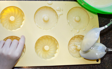 pouring liquid muffin batter into silicone baking mold. making dessert at home. tasty food for kids and adults