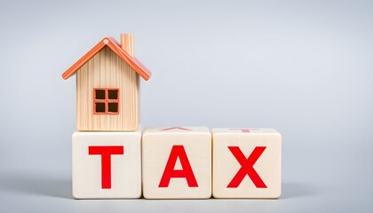 A miniature wooden house rests on white blocks spelling out the word TAX, symbolizing property tax.