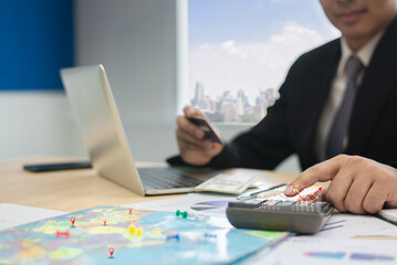 Close-up of a businessman using a calculator, laptop, and credit card while planning travel...