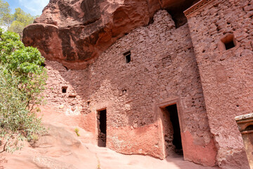 The historic rock-hewn dwellings of the Sant Gregori Hermitage, built into red sandstone cliffs in Priorat, Spain