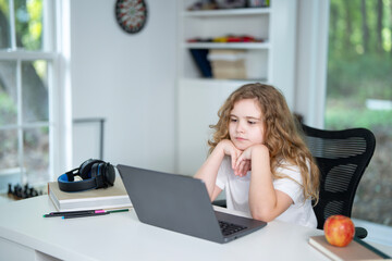 Kid studying at home school with laptop and books. Child doing homework during homeschool lesson. Young student learning in home school environment. Boy focused on study at home school desk.