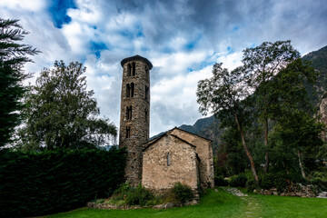 Naklejka premium The historic Santa Coloma church with its unique round Romanesque bell tower and apse, set against a dramatic sky in the mountains of Andorra