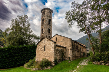 Fototapeta premium The historic Santa Coloma church with its unique round Romanesque bell tower and apse, set against a dramatic sky in the mountains of Andorra